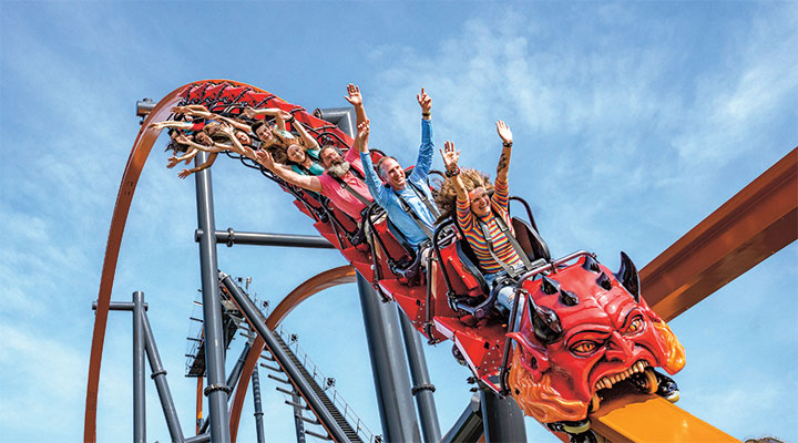 Photo of people with their hands up riding a rollercoaster